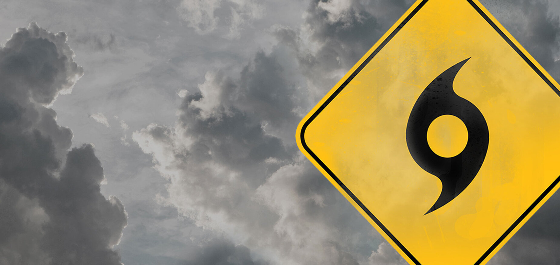 Warning sign for a hurricane with storm clouds in the background.